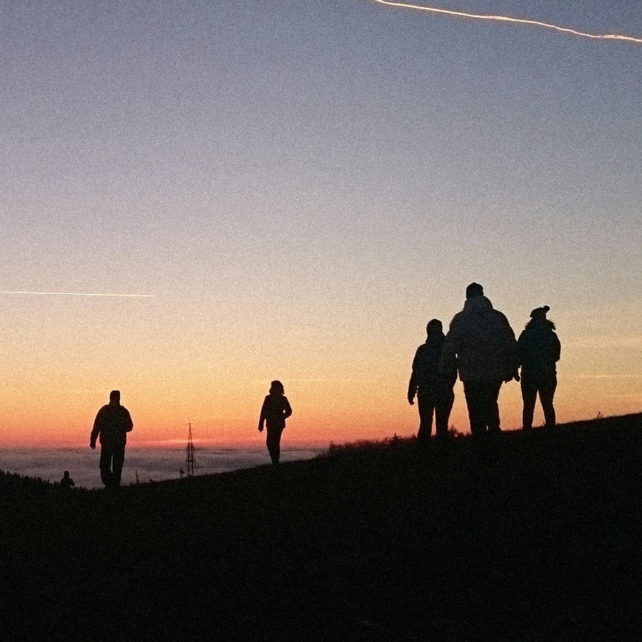 Un gruppo di persone cammina su un crinale al tramonto